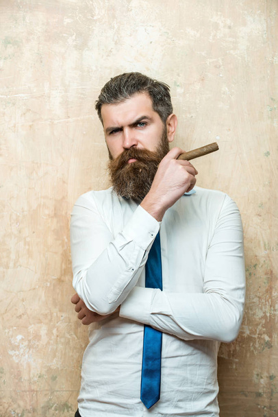 bearded man on serious face smoking cigar - Фото, зображення