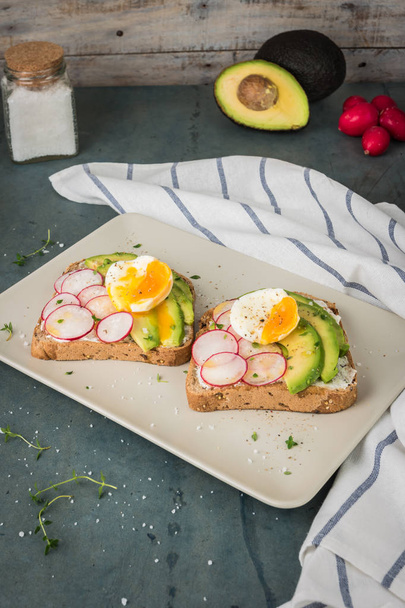 Sandwiches with avocado radish cheese and eggs on a rye bread on - 写真・画像