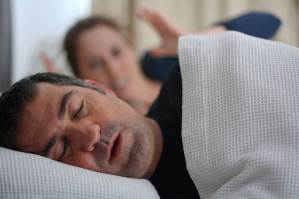 Nainen kärsii hänen miespuolinen kumppani kuorsaus sängyssä
 - Valokuva, kuva