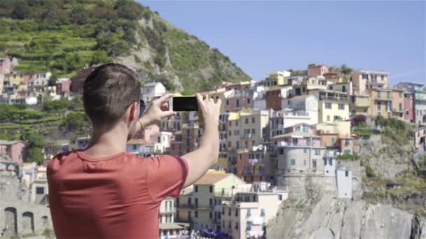 Mladý muž si vyfotit krásný výhled na staré vesnici v Cinque Terre, Liguria, Itálie. Evropská Italská dovolená. - Záběry, video