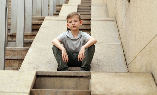 Triste garçon assis sur un grand escalier en granit - style urbain
 - Photo, image