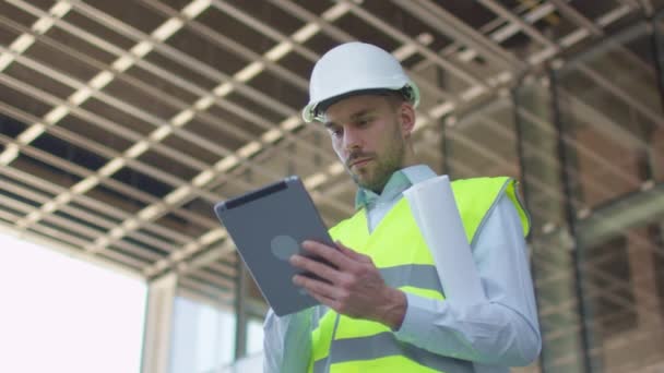 Male Engineer Using Tablet Computer. Glass Building or Skyscraper under Construction on Background. - Felvétel, videó