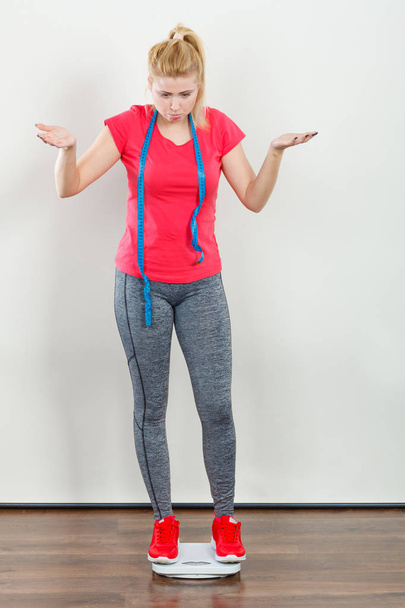 Woman wearing sportswear standing on weight machine - Foto, afbeelding