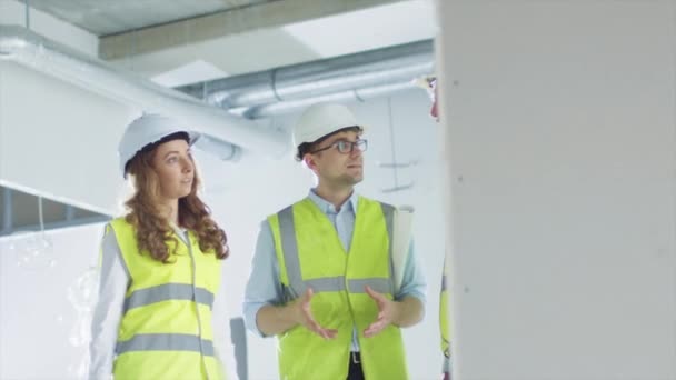 Team of Engineers in Hard Hats Having Conversation, Looking at Blueprint, inside Building Under Construction. - Video, Çekim