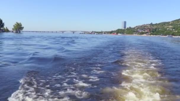 Filming from the stern of the ship. Summer river landscape. The Volga river in Saratov, Russia.  Road bridge between the cities of Saratov and Engels. The sound of the boat motor. Footage clip 4K - Video