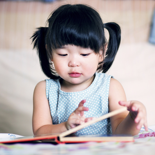 Чарівна і прекрасна азіатська дитина читає книгу
  - Фото, зображення