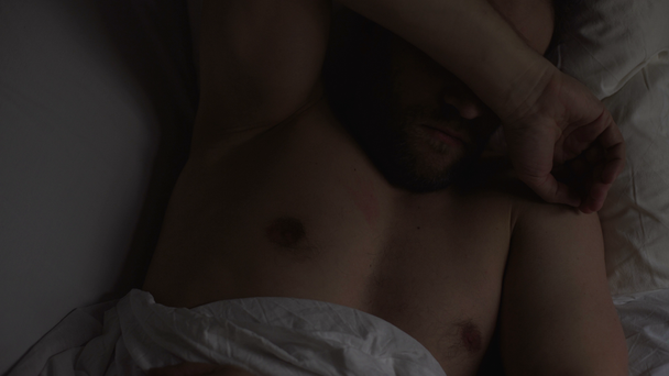 Felnőtt ember, miután egy rossz rémálom, esztergálás ágyon alszik. Stressz és alváshiány - Felvétel, videó