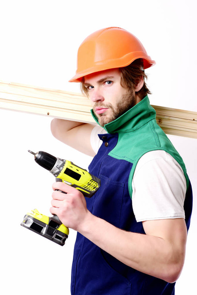 Construction worker holds wooden boards on shoulder and yellow drill - Foto, immagini