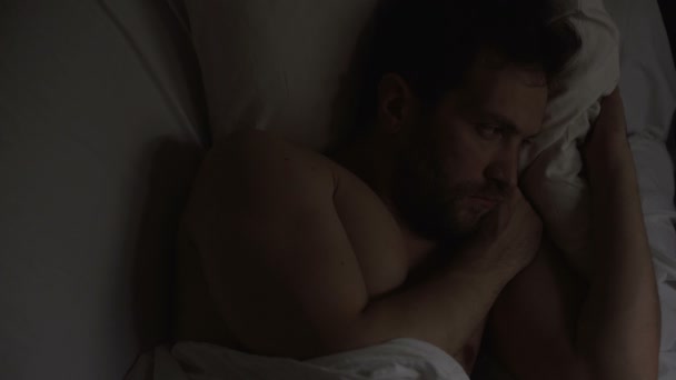 Aufgebrachter Mann mit Impotenz liegt im Bett und kann nicht schlafen, weil er an Probleme denkt - Filmmaterial, Video