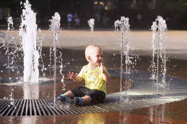 Criança bonito brincando com córregos de água na fonte
 - Foto, Imagem