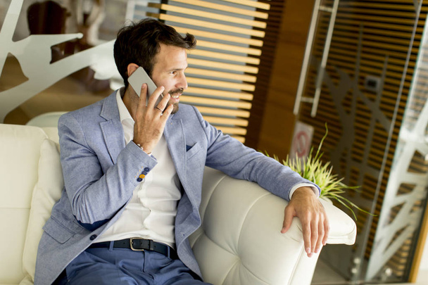 Handsome businessman in suit speaking on the phone in office - Foto, afbeelding