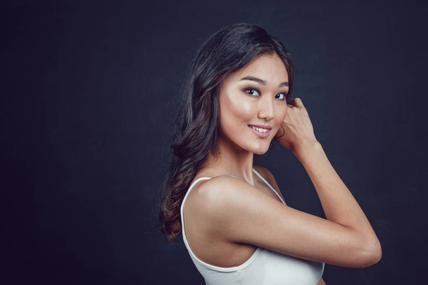 Portrait of a beautiful asian woman with makeup and light curls on black background. - 写真・画像