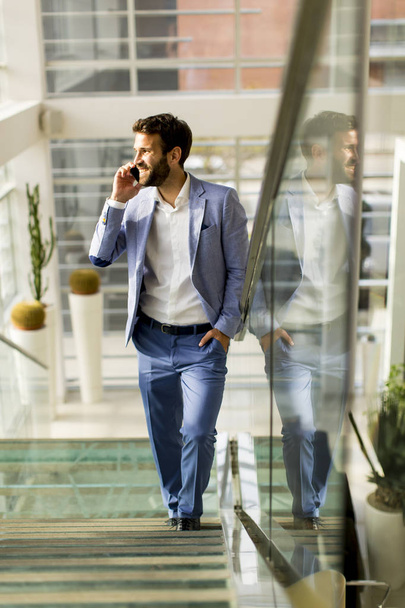 Hombre de negocios guapo de traje hablando por teléfono en la oficina - Foto, imagen