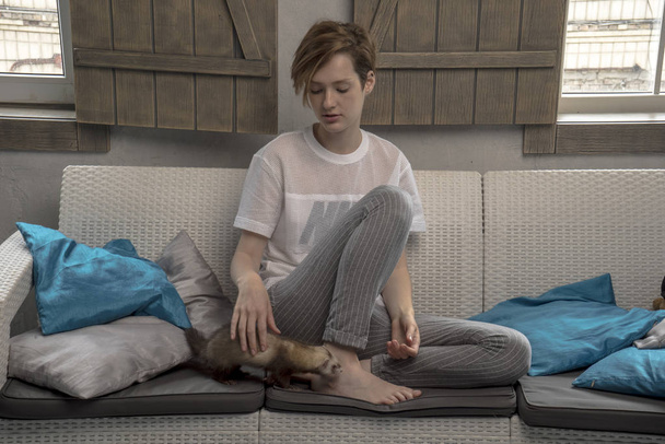 Girl with ferret on bed. Girl with an animal. Cute ferret - Фото, зображення