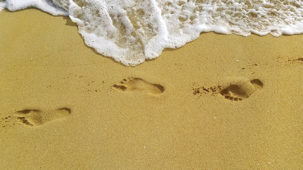 Espuma marina y huellas en la arena de la playa
 - Foto, imagen
