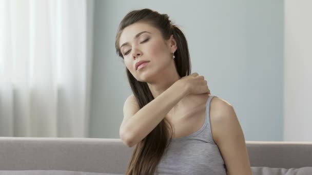 Young female massaging neck and shoulders, releasing disturbing pain, stiff neck - Video, Çekim