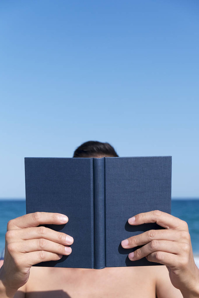 man lezen van een boek op het strand - Foto, afbeelding