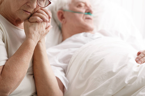 Senior man in hospital bed and his wife holding his hand - Foto, Imagen
