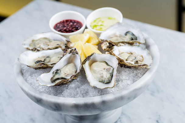 Fresh oysters platter with sauce and lemon - Foto, Bild