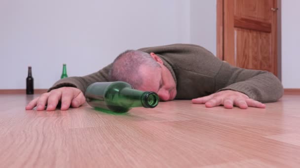 Ruchome butelkę alkoholu w pobliżu pijany mężczyzna na piętrze - Materiał filmowy, wideo