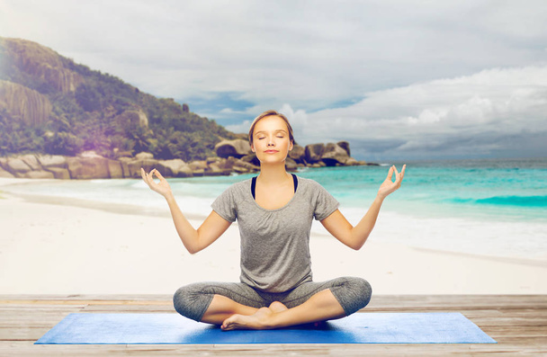 woman doing yoga meditation in lotus pose on beach - Foto, imagen