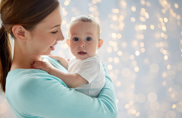 happy young mother with little baby over lights - Photo, Image