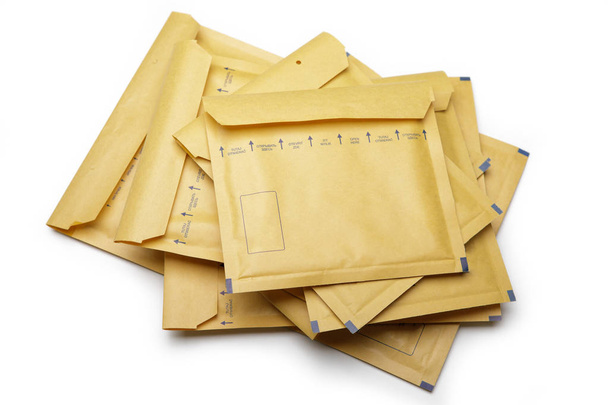 Пачка желтых упаковочных конвертов на белом фоне
 - Фото, изображение
