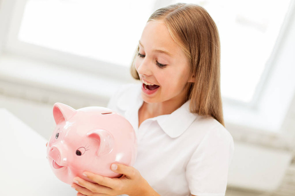 happy girl with piggy bank at home - Foto, Imagem