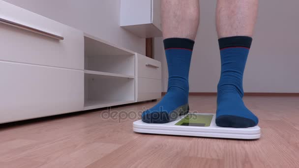 Hombre en calcetines con sobrepeso de pie en la balanza
 - Imágenes, Vídeo