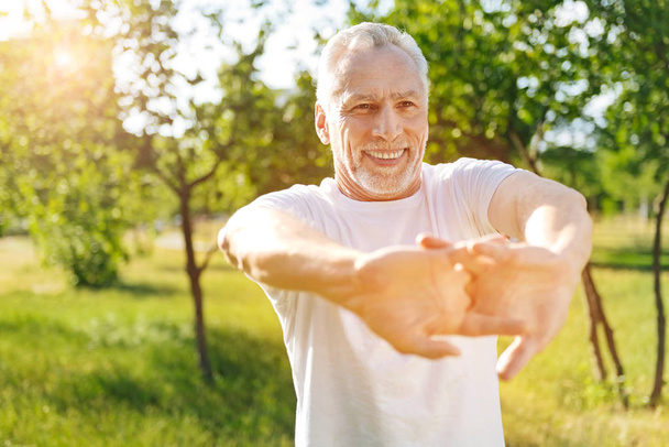 Delighted retired man doing stretching exercises - Photo, Image