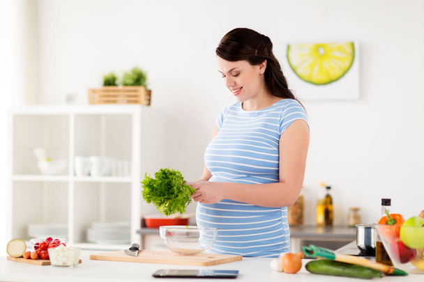 pregnant woman cooking vegetable salad at home - Photo, Image