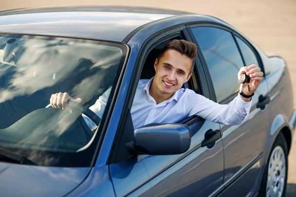Ευτυχής αγοραστής κρατώντας τα κλειδιά του αυτοκινήτου στο εσωτερικό του νέου οχήματος - Φωτογραφία, εικόνα
