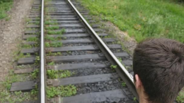 mladý muž s kufrem na železniční trati. Vlak ztratí ve velkém městě, mladý muž jde ztratit se ve velkoměstě - Záběry, video