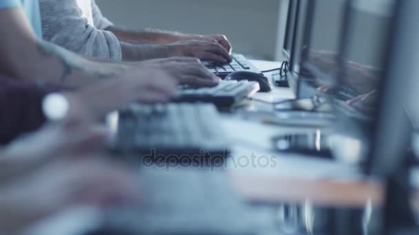 Μικτή φυλή νέοι άνθρωποι είναι κάθεται σε μια σειρά και εργάζονται σε υπολογιστές. Πληκτρολόγηση σε πληκτρολόγιο. - Πλάνα, βίντεο