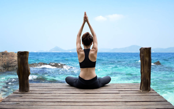 Healthy woman lifestyle exercising vital meditate and  practicing yoga at seashore, nature background.  Healthy Concept. - Photo, image