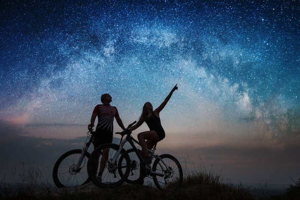 Coppia ciclisti con mountain bike di notte sotto il cielo stellato
 - Foto, immagini
