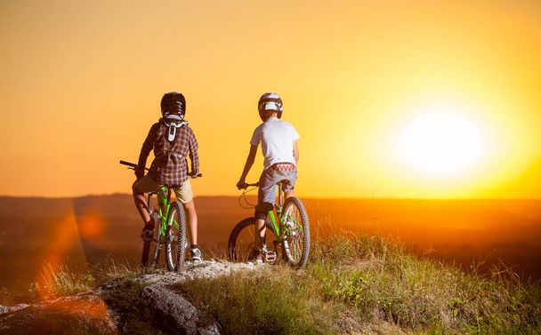 Cyclists with mountain bikes on the hill in the evening - Photo, Image