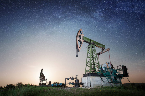 Нефтяной насос на нефтяном месторождении ночью
 - Фото, изображение