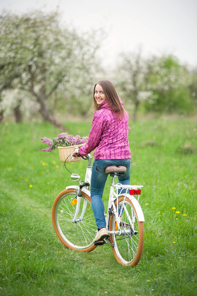 Ciclista donna in sella ad una bicicletta bianca vintage nel giardino primaverile
 - Foto, immagini