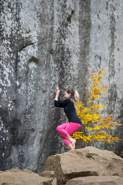 Mujer deportiva en forma está practicando yoga en la roca en la naturaleza
 - Foto, imagen