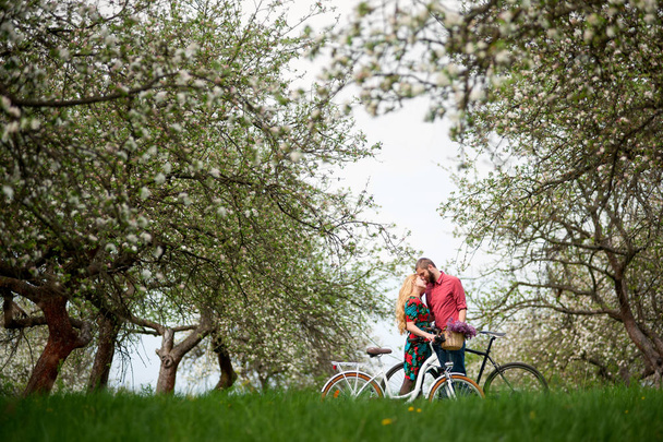 Amare giovane coppia con biciclette in giardino primaverile
 - Foto, immagini