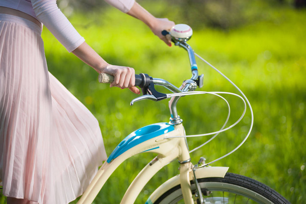 Hermosa ciclista femenina con bicicleta retro en el jardín de primavera
 - Foto, imagen