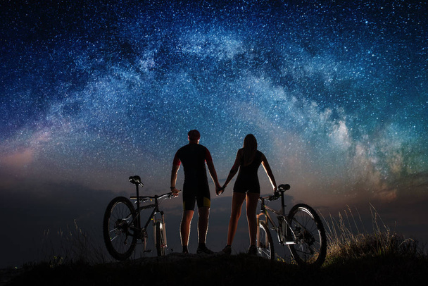 Pár cyklistů s horských kol v noci pod hvězdnou oblohou - Fotografie, Obrázek