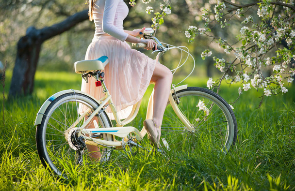 Bella ciclista donna con bicicletta retrò nel giardino primaverile
 - Foto, immagini