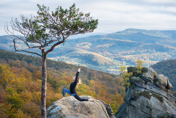 Sporty fit woman is practicing yoga on the top of the mountain - Photo, Image