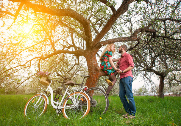 Loving young couple with bicycles in spring garden - 写真・画像