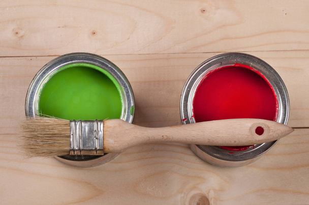 зеленая и красная краска в банке для ремонта и кисти на светлом деревянном фоне
 - Фото, изображение