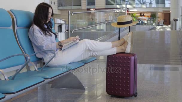 Jeune femme dans un livre de lecture de salon d'aéroport en attendant l'avion de vol
. - Séquence, vidéo
