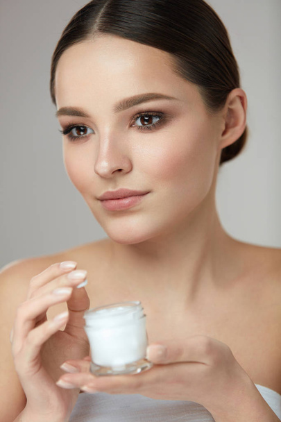 Face Beauty Care. Woman With Natural Makeup Holding Cream - Foto, Imagen