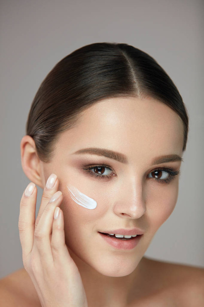 Beauty Cosmetics. Woman Putting Cosmetic Cream On Beautiful Face - Fotoğraf, Görsel